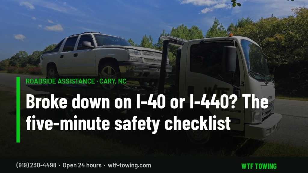WTF Towing rollback carrier loading a pickup on a grassy roadside shoulder in Cary, NC — roadside assistance and interstate breakdown towing on I-40 and I-440