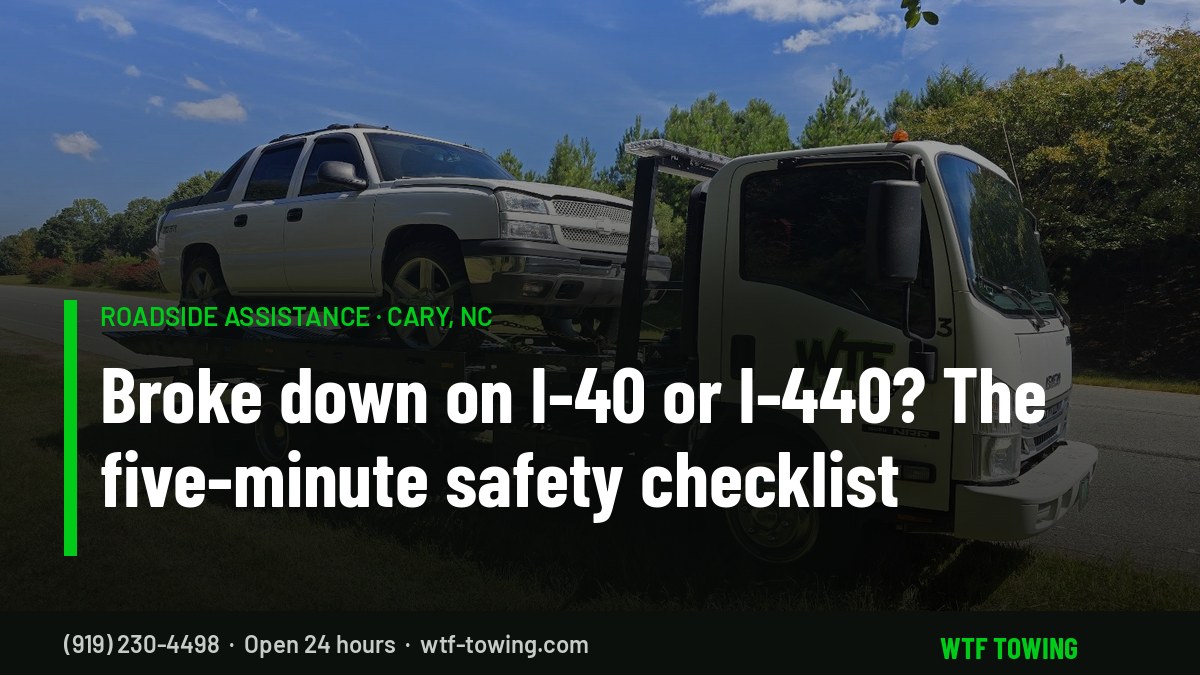 WTF Towing rollback carrier loading a pickup on a grassy roadside shoulder in Cary, NC — roadside assistance and interstate breakdown towing on I-40 and I-440